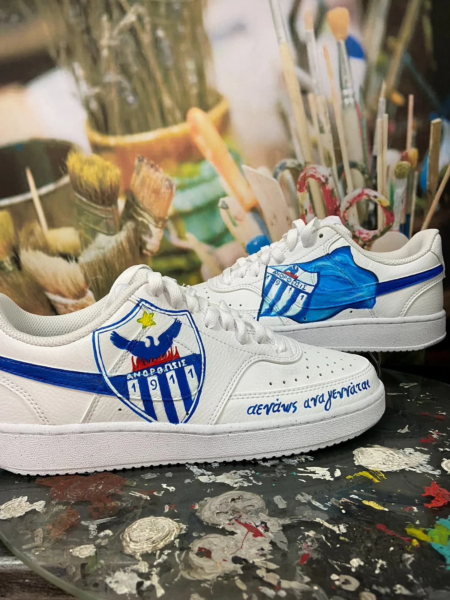Λευκά sneakers με ζωγραφισμένο το έμβλημα της Ανόρθωσης με τον φοίνικα και μπλε swoosh