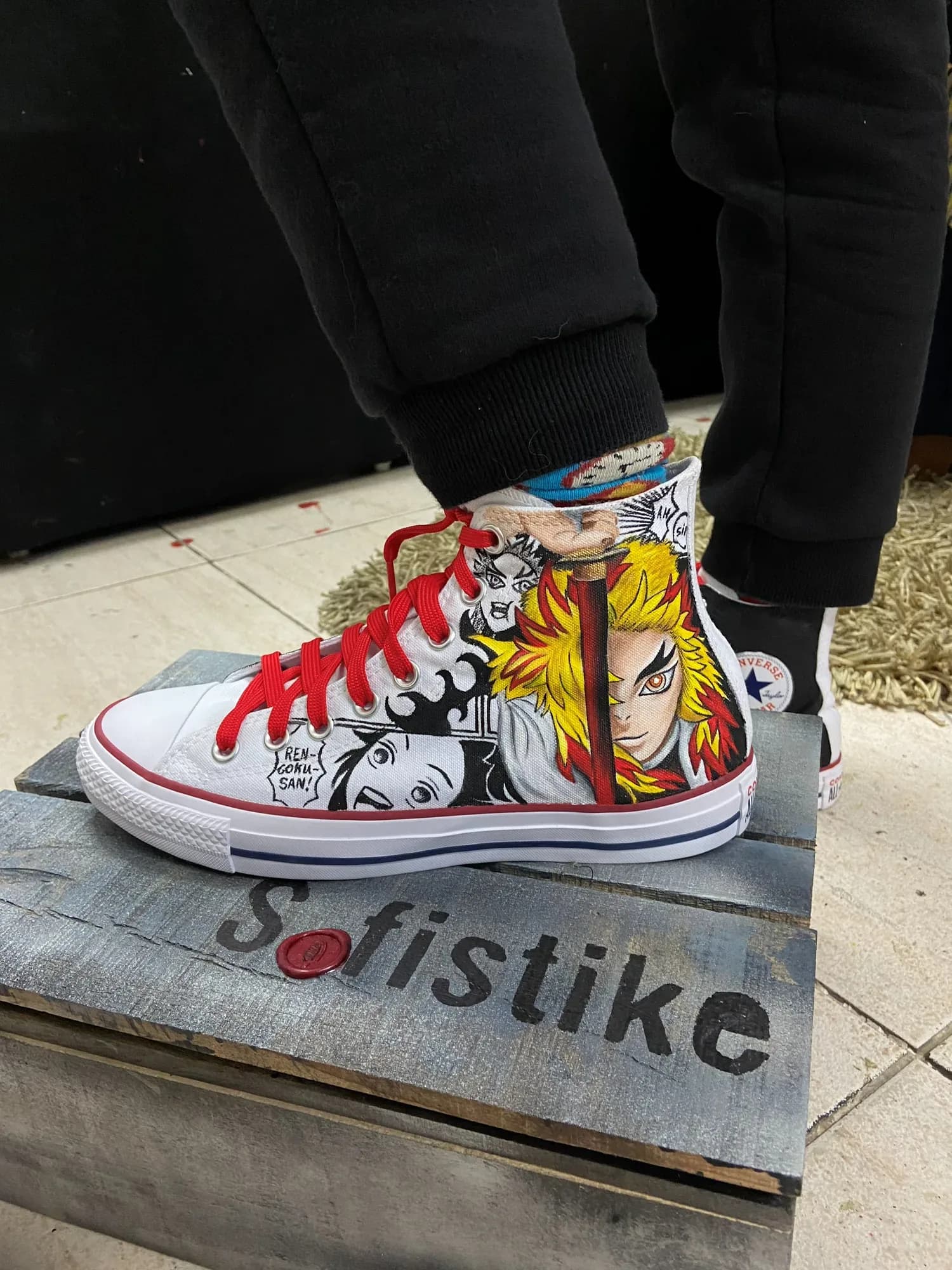 Φορεμένο λευκό ψηλό sneaker με κόκκινα κορδόνια και ζωγραφισμένα καρέ manga με ήρωα anime